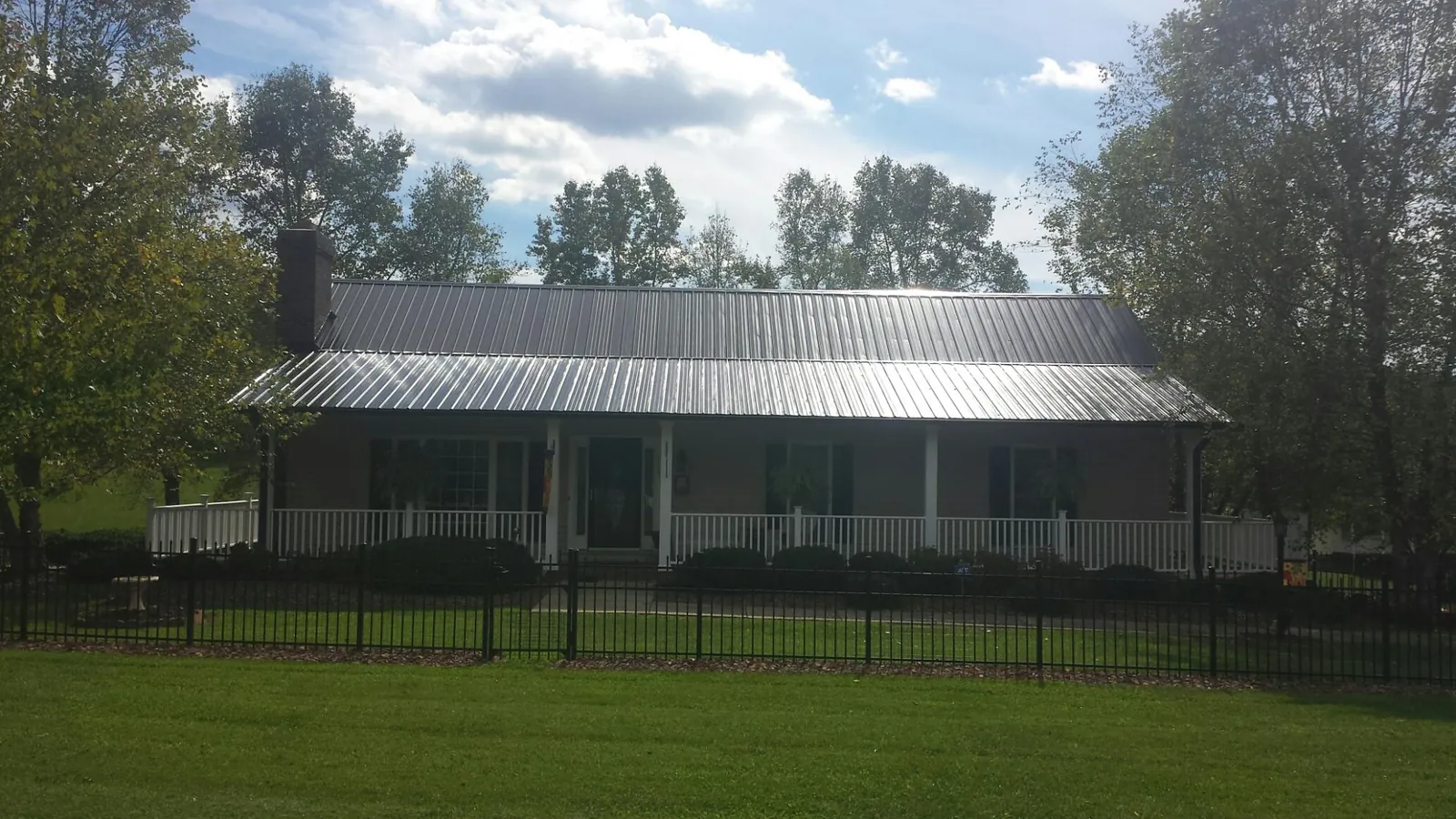 Gray metal roof on a brick ranch with a full width front porch — Gutter Guard Installation work by our crew in Cobalt