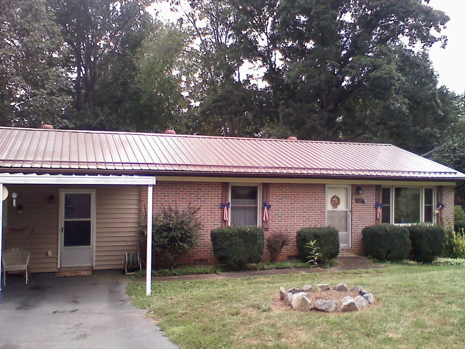 Bronze metal roof and carport on a brick ranch home — Roof Repair work by our crew in Cobalt