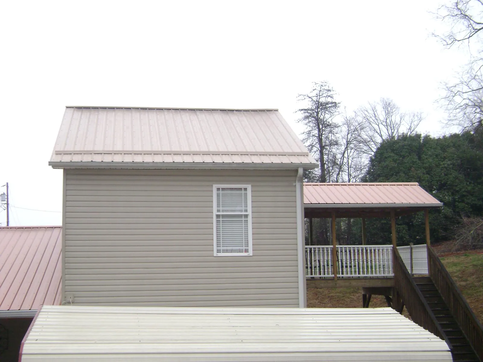 Tan metal roofs on a two story addition and attached porch, from a Roof Replacement job in Cobalt