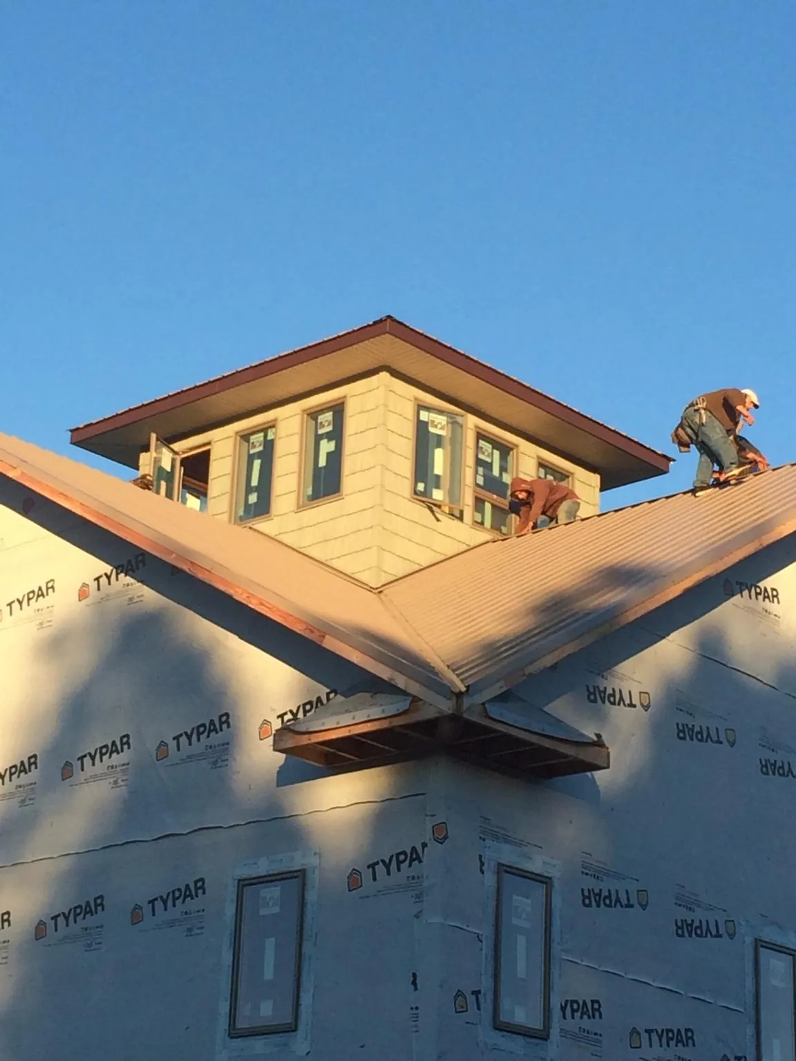 Roofers working around a rooftop cupola on a new metal roof at sunset — Roof Waterproofing in Cobalt by Roofing Brothers